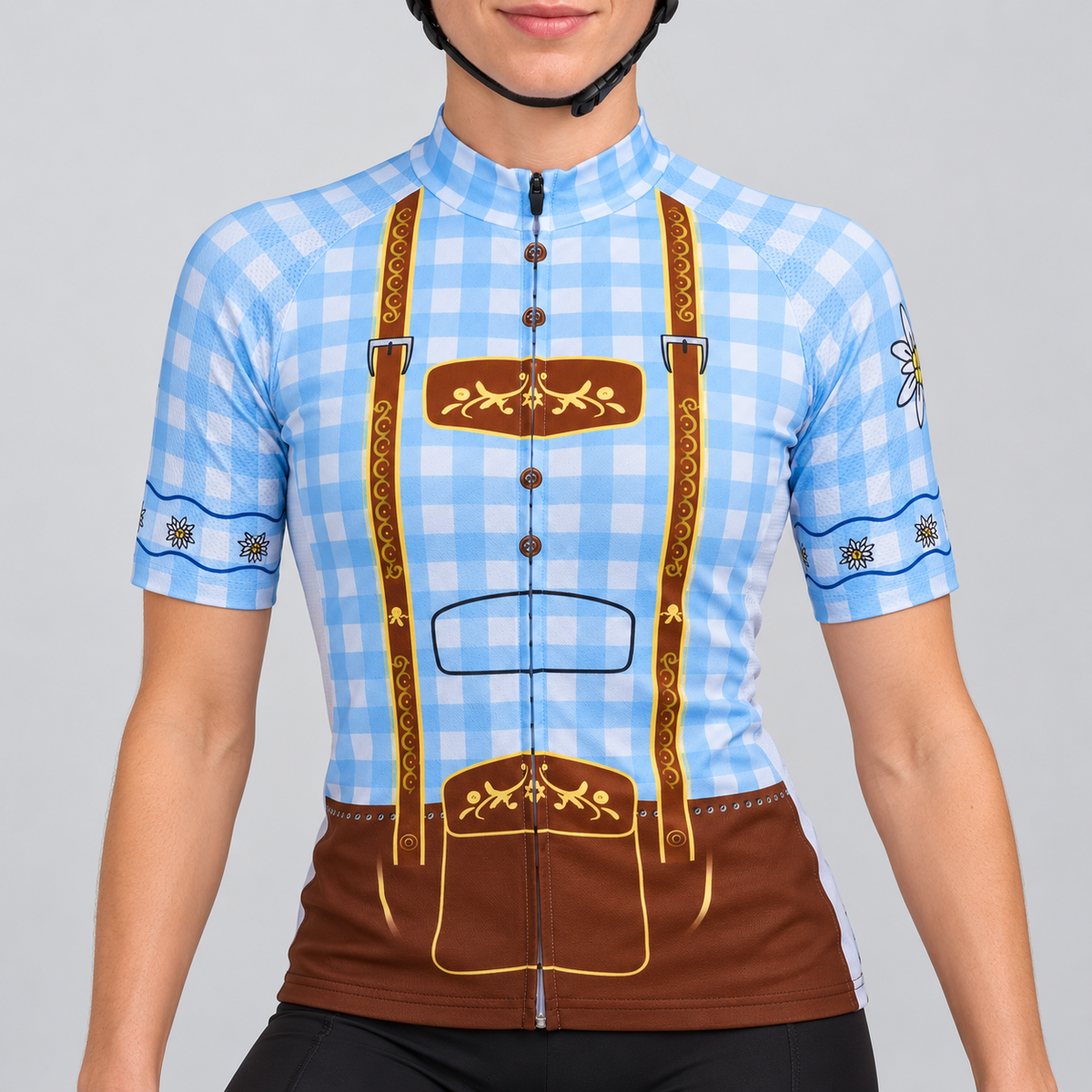Female model wearing the pale blue and white checked short-sleeve Blue Lederhosen cycling jersey with printed brown braces, floral folk motifs and edelweiss sleeve details, shown with black cycling shorts against a light grey studio background.