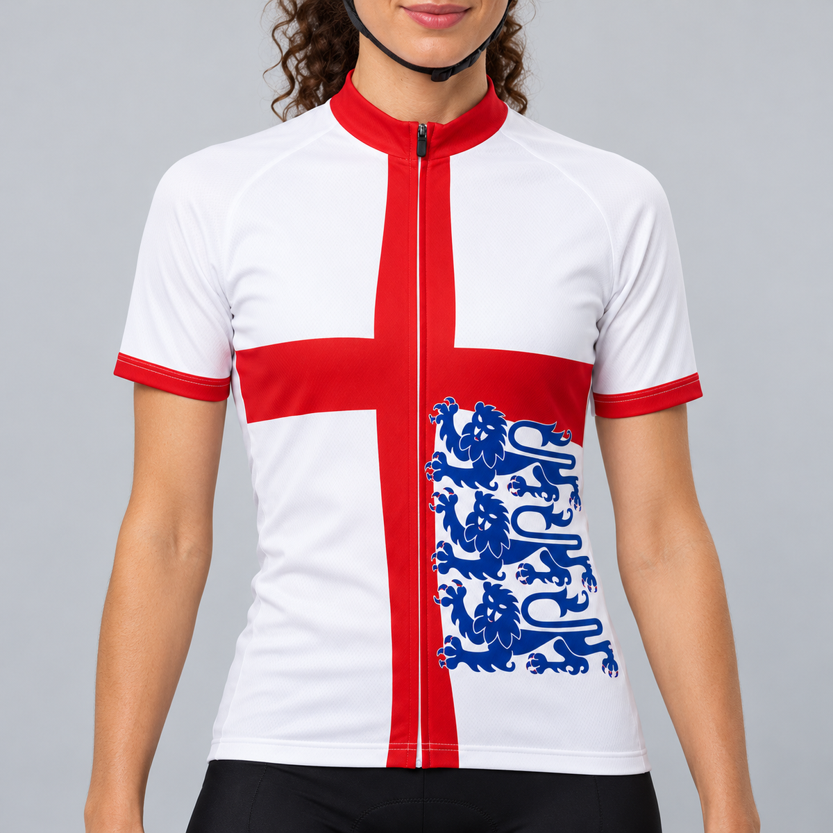 Female model wearing the white short-sleeve England Flag 3 Lions cycling jersey with a red St George cross, three blue lions and black cycling shorts against a light neutral studio background.