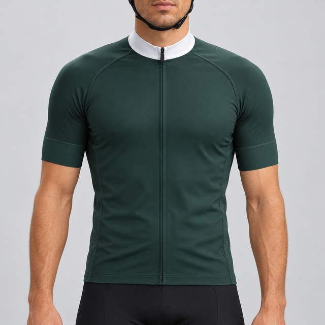Male model wearing the dark green short-sleeve GG BASICS cycling jersey with a white collar, matching green cuffs and mesh side panels, shown with black cycling shorts against a light grey studio background.