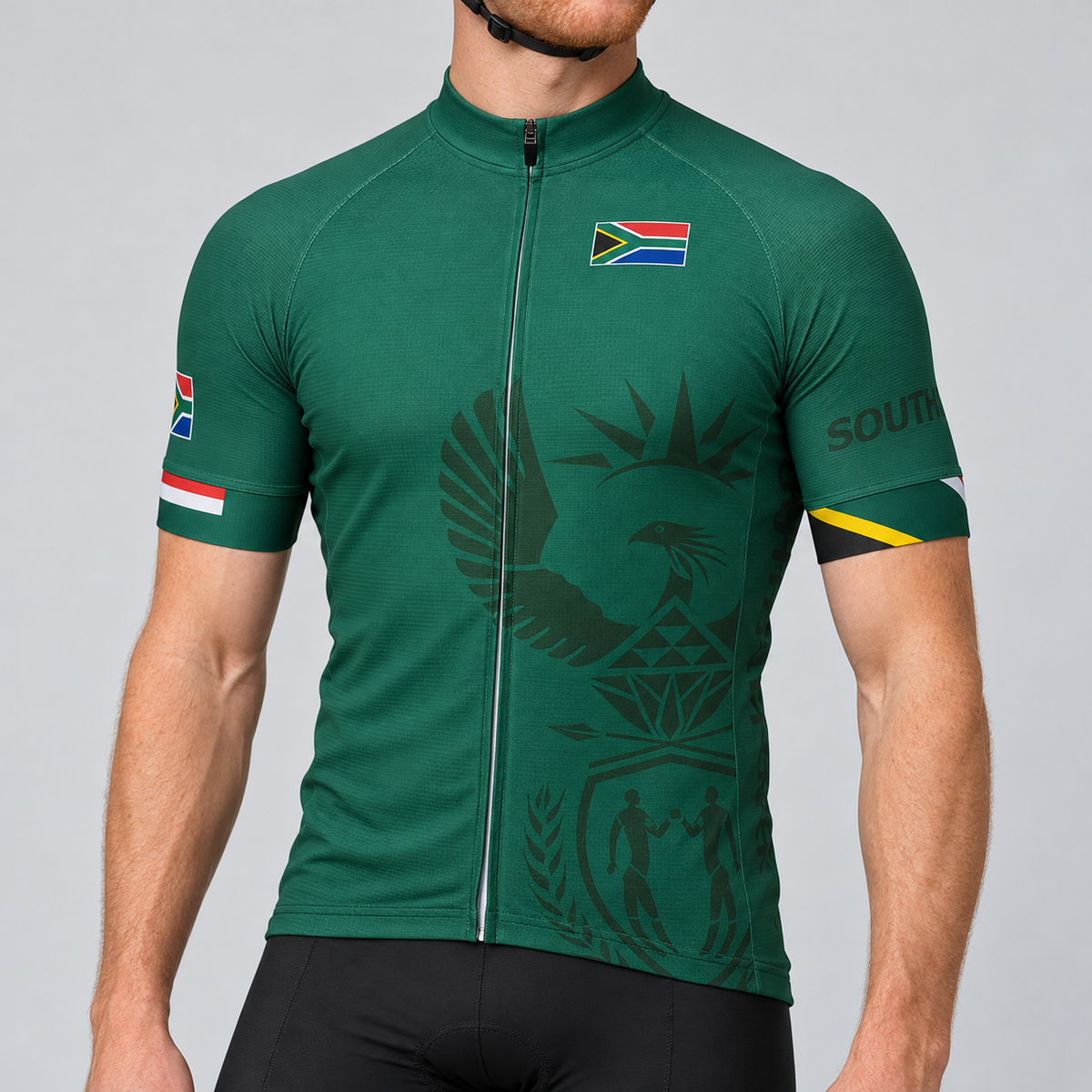 Male model shown from the chin down wearing the deep green South Africa short-sleeve cycling jersey with tonal national emblem and flag details against a light grey studio background.