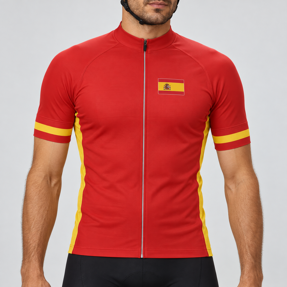 Male model shown from the chin down wearing the red Spain 2024 football-inspired short-sleeve cycling jersey with yellow sleeve bands, yellow side panels and a Spanish flag chest patch against a light grey studio background.