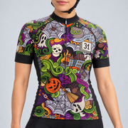 Female model wearing the short-sleeve 31st October Halloween cycling jersey with colourful spooky graphics and black cycling shorts, shown from the lower lip and chin down against a light grey studio background.
