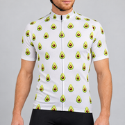 Male model wearing the white short-sleeve Avocado Pattern cycling jersey with repeating green avocado graphics and black cycling shorts, shown from the chin down against a neutral studio background.