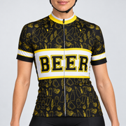 Female model wearing the black, white and yellow short-sleeve Beer cycling jersey with BEER lettering and beer-themed line graphics, shown from the lower lip and chin down with black cycling shorts against a light grey studio background.