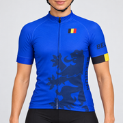 Female model wearing the royal blue short-sleeve Belgium cycling jersey with dark lion graphic, Belgian flag details and black cycling shorts, shown from the lower lip and chin down against a light grey studio background.