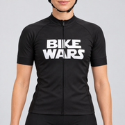 Female model wearing the black short-sleeve Bike Wars cycling jersey with bold white BIKE WARS lettering and black cycling shorts, shown from the lower lip and chin down against a light grey studio background.