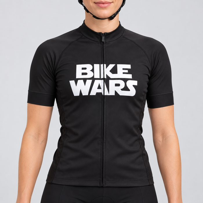 Female model wearing the black short-sleeve Bike Wars cycling jersey with bold white BIKE WARS lettering and black cycling shorts, shown from the lower lip and chin down against a light grey studio background.