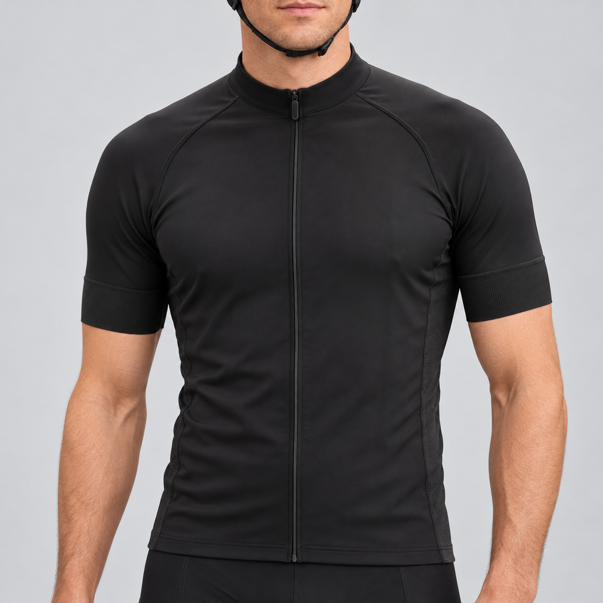 Male model wearing the plain black short-sleeve GG BASICS cycling jersey with black collar, cuffs and side panels, shown from the chin down with black cycling shorts against a neutral studio background.