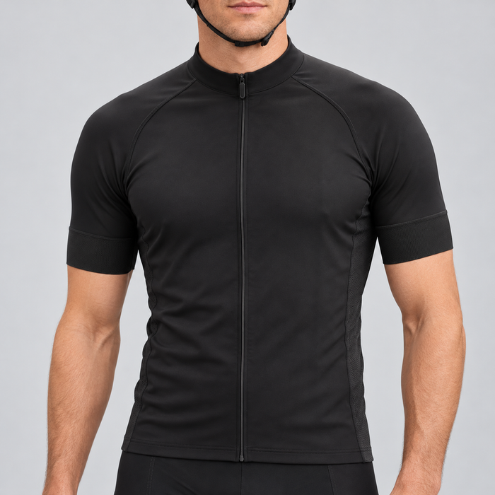 Male model wearing the plain black short-sleeve GG BASICS cycling jersey with black collar, cuffs and side panels, shown from the chin down with black cycling shorts against a neutral studio background.