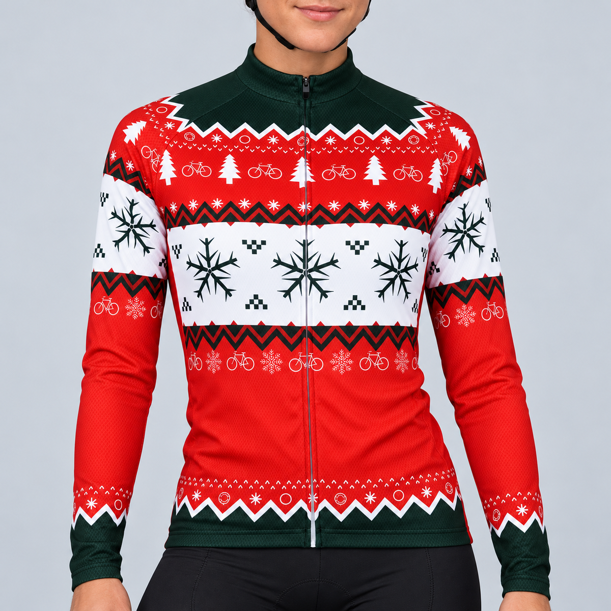 Female model wearing the red, white and dark-green long-sleeve Christmas Jumper cycling jersey with bicycle, tree, snowflake and knitted-effect bands, shown with black cycling shorts against a light grey studio background.