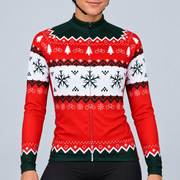Female model wearing the red, white and dark-green long-sleeve Christmas Jumper cycling jersey with bicycle, tree, snowflake and knitted-effect bands, shown with black cycling shorts against a light grey studio background.