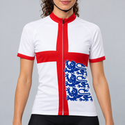 Female model wearing the white short-sleeve England Flag 3 Lions cycling jersey with a red St George cross, three blue lions and black cycling shorts against a light neutral studio background.