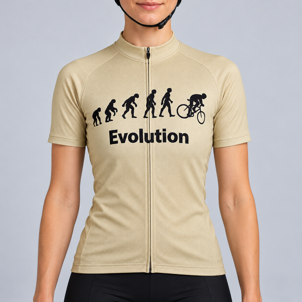 Female model wearing the beige short-sleeve Evolution Of Man cycling jersey with black evolution silhouettes, cyclist graphic and Evolution wording, shown with black cycling shorts against a light neutral studio background.