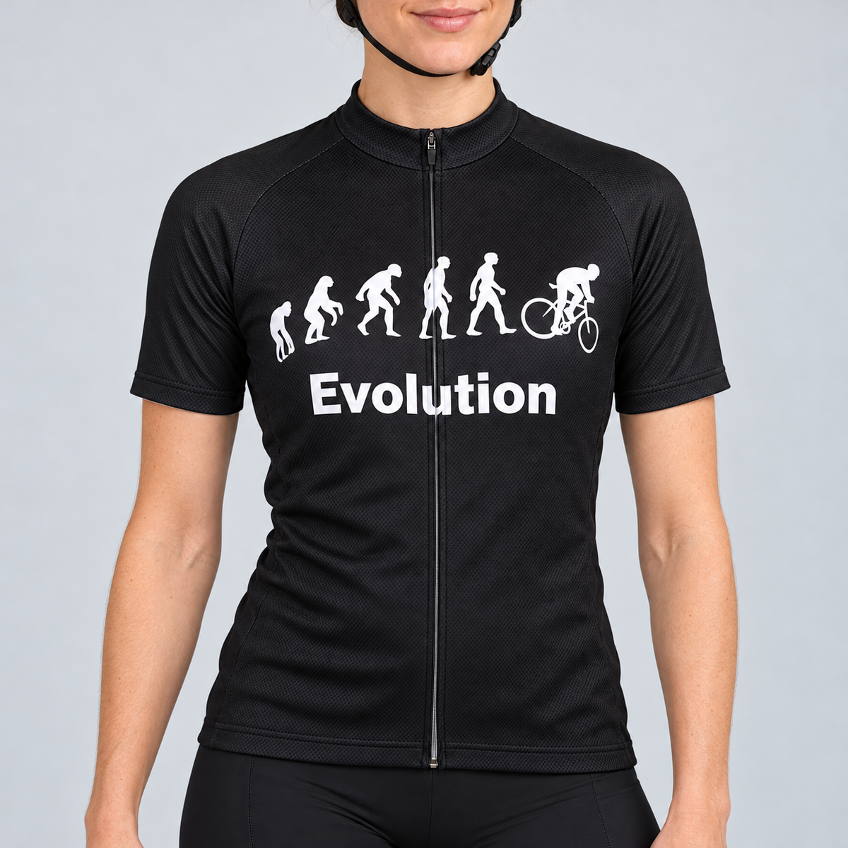 Female model wearing the black short-sleeve Evolution Of Man cycling jersey with white evolution silhouettes, cyclist graphic and Evolution wording, shown with black cycling shorts against a light neutral studio background.