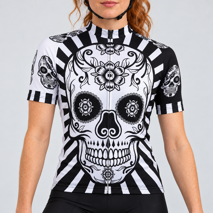 Female model wearing the black and white short-sleeve Flower Skull Print cycling jersey with floral skull graphics and striped trim, shown from the lower lip down with black cycling shorts against a light grey studio background.