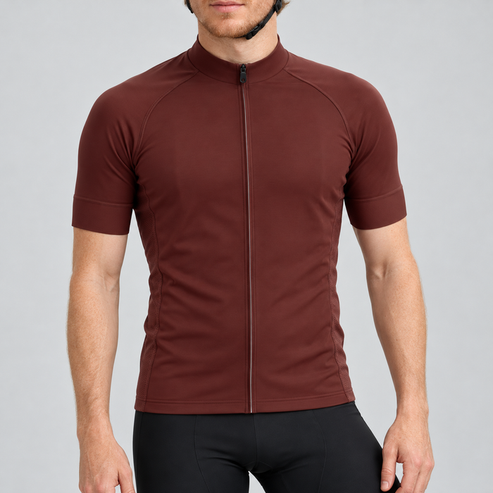 Male model wearing the plain burgundy short-sleeve GG BASICS cycling jersey with matching collar and cuffs and mesh side panels, shown with black cycling shorts against a light grey studio background.
