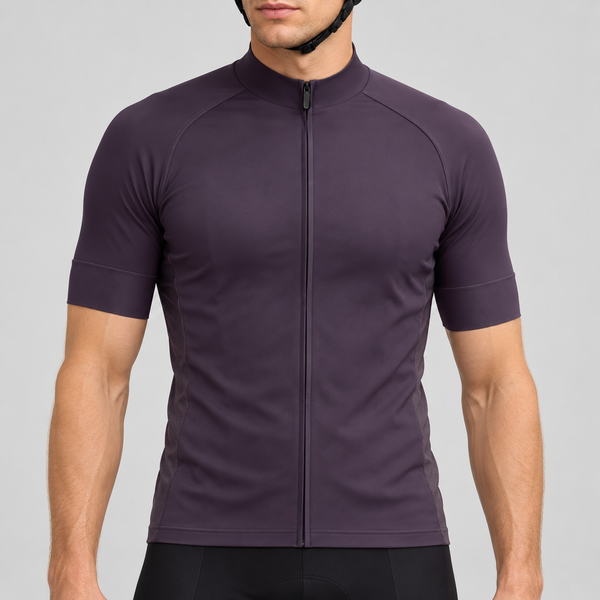 Male model wearing the plain dark purple short-sleeve GG BASICS cycling jersey with matching collar and cuffs and mesh side panels, shown with black cycling shorts against a light grey studio background.