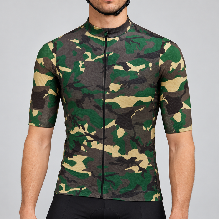 Male model shown from the chin down wearing the green, khaki, brown and charcoal camouflage short-sleeve cycling jersey with black cycling shorts against a light grey studio background.