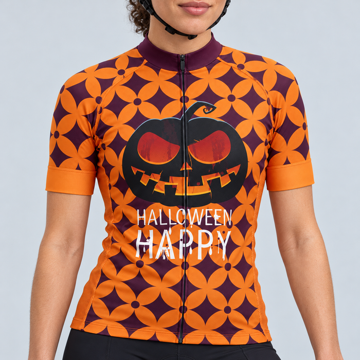 Female model wearing the burgundy-purple and orange short-sleeve Halloween Happy cycling jersey with black jack-o-lantern artwork and white HALLOWEEN HAPPY lettering, shown with black cycling shorts against a light grey studio background.