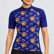 Female model wearing the navy short-sleeve Dog and Hearts Pattern cycling jersey with brown-and-white dog faces, white heart motifs and black cycling shorts against a light neutral studio background.