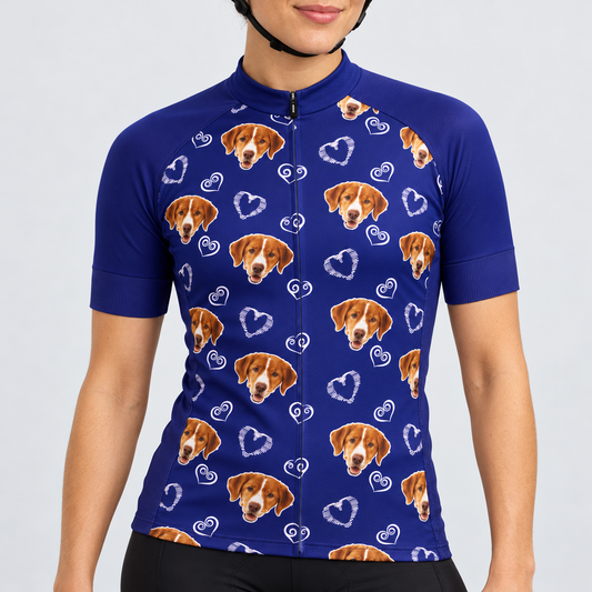 Female model wearing the navy short-sleeve Dog and Hearts Pattern cycling jersey with brown-and-white dog faces, white heart motifs and black cycling shorts against a light neutral studio background.