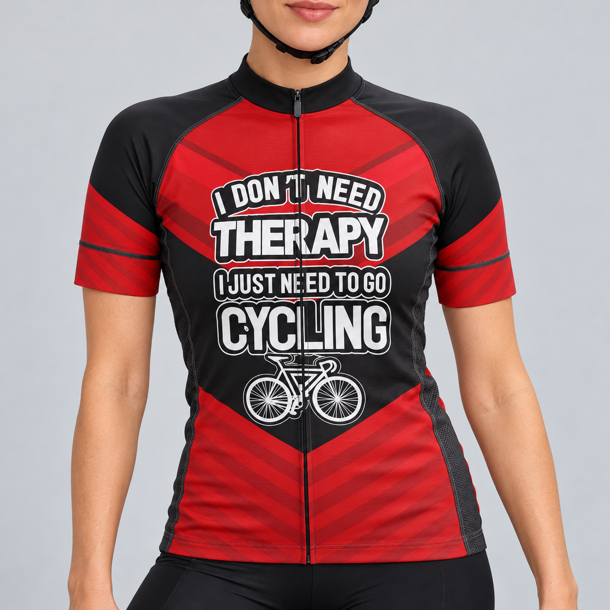 Female model wearing the red and black short-sleeve No Need For Therapy cycling jersey with white slogan lettering and bicycle graphic, shown with black cycling shorts against a light grey studio background.