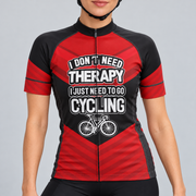 Female model wearing the red and black short-sleeve No Need For Therapy cycling jersey with white slogan lettering and bicycle graphic, shown with black cycling shorts against a light grey studio background.
