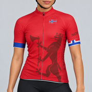 Female model wearing the red short-sleeve Norway cycling jersey with Norwegian flag crest, dark red crowned lion-and-axe graphic, flag-colour sleeve cuffs and black cycling shorts against a light grey studio background.