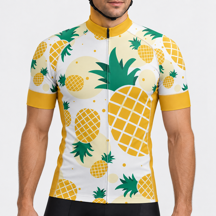 Male model wearing the ivory, mustard yellow and green pineapple print short-sleeve cycling jersey against a light grey studio background.