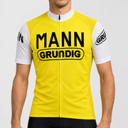 Male model wearing the yellow Dr. Mann Grundig short-sleeve retro cycling jersey with white collar and sleeves and black MANN GRUNDIG lettering, shown from the chin down against a neutral studio background.