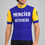Male model wearing the blue and yellow Retro Mercier Hutchinson short-sleeve cycling jersey against a light grey studio background.