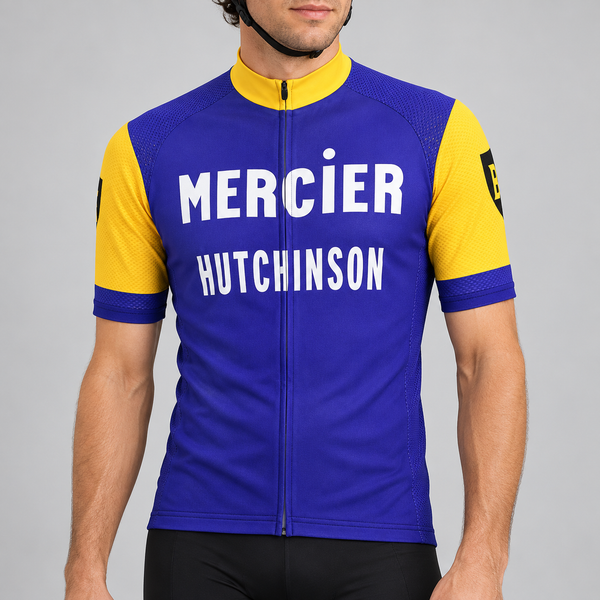 Male model wearing the blue and yellow Retro Mercier Hutchinson short-sleeve cycling jersey against a light grey studio background.