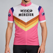 Male model wearing the pink and white Retro Miko Cycles Mercier short-sleeve cycling jersey with orange and yellow chevrons against a grey studio background.