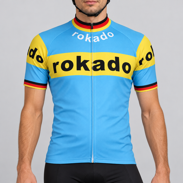 Male model shown from the chin down wearing the sky-blue and yellow Retro Rokado short-sleeve cycling jersey against a light grey studio background.