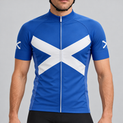 Male model shown from the chin down wearing the royal-blue Scotland Saltire short-sleeve cycling jersey against a light grey studio background.
