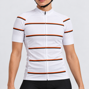 Female model wearing the white short-sleeve GG BASICS White Hoops cycling jersey with orange and black horizontal stripes, shown with black cycling shorts against a light grey studio background.